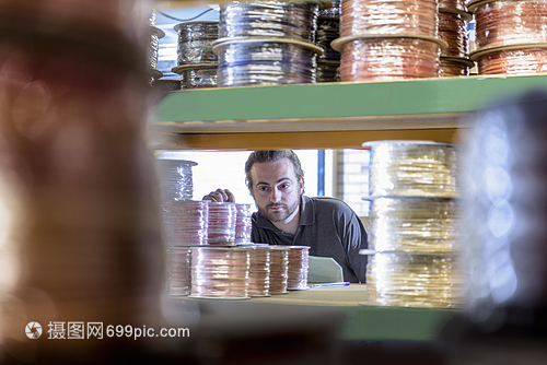 在电缆工厂从货架上选择产品的工人